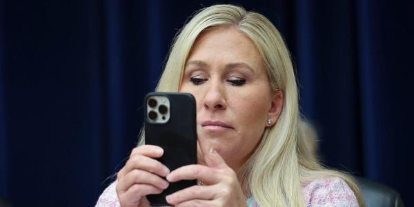 Republican Rep. Marjorie Taylor Greene of Georgia uses her phone during a hearing on April 18, 2023.