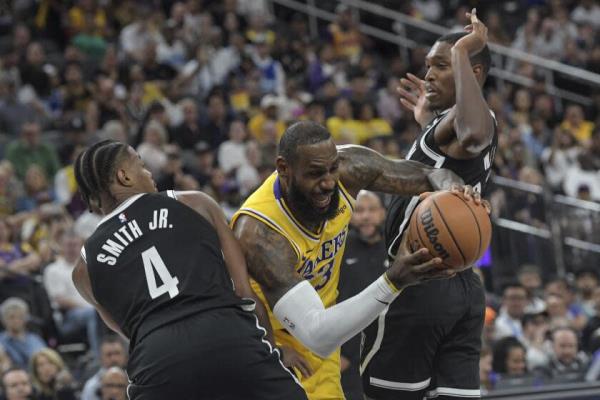 Los Angeles Lakers forward LeBron James, center, drives between Brooklyn Nets guards Dennis Smith Jr. (4) and Lo<em></em>nnie Walker IV, right, during the first half of a preseason NBA basketball game Monday, Oct. 9, 2023, in Las Vegas. (AP Photo/Sam Morris)