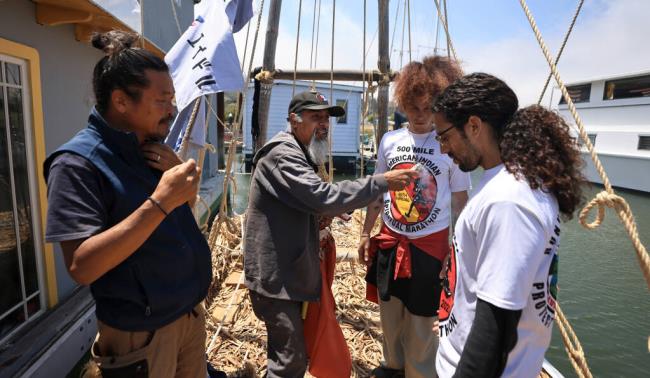 Blessing a 30-foot tule boat docked in Sausalito, Joe Weber, a tribal member of the Big Valley Rancheria in Lake County smudges Manu Tonantzan, middle, and Alex Estrada, Tuesday, June 27, 2023. At left is internatio<em></em>nally known boat builder Jin Ishikawa, who is helping to build a larger 60-foot tule boat which will be sailed across the Pacific Ocean. The tules were gathered from the shores of Clear Lake  (Kent Porter / The Press Democrat)
