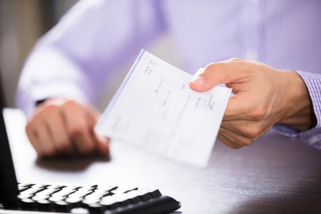 Close-up Of A Businessperson's Hand Holding paycheck In Office (Andrey_Popov / Shutterstock)